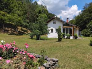 una casa bianca con fiori nel cortile di Palučak 30 a Babice Gornje