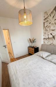 a bedroom with a white bed and a chandelier at Apartament Grochowa in Białystok