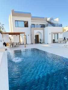 a villa with a swimming pool in front of a house at Villa VIP in Midoun