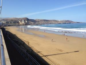 un groupe de personnes sur une plage près de l'océan dans l'établissement Apartamento Beach Loft Las Canteras, à Las Palmas de Gran Canaria