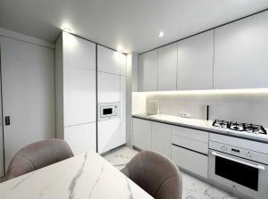 a kitchen with white cabinets and a table and chairs at Білі апартаменти in Dnipro