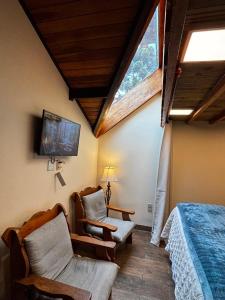 a bedroom with a bed and a chair and a window at Chalé Coração de Monte Verde in Monte Verde