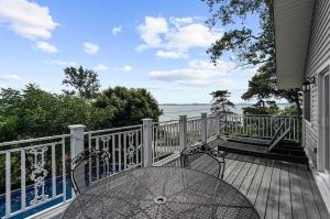 a table and chairs on a deck with a view of the water at Waterfront Cottage w Pool Beach Access in Fort Erie
