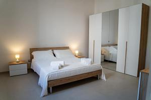 a bedroom with a large white bed with two lamps at Dimora Noè e Concettina in Botrugno +20 photos