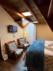 a bedroom with a bed and chairs in a room at Chalé Coração de Monte Verde in Monte Verde