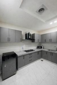 a kitchen with white cabinets and a stove top oven at Second Stay apartments in Faisalabad
