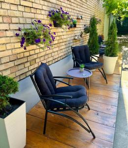 a patio with three chairs and a table and flowers at 'MONAS' mini apartments in Sombor
