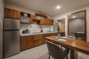 a kitchen with a wooden table and a stainless steel refrigerator at Suite Deluxe con piscina privada en Valladolid - Penca Leonor 11 in Valladolid