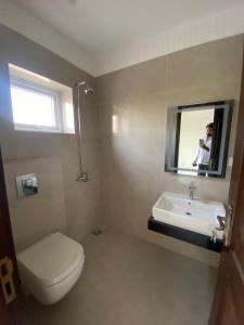 a bathroom with a toilet and a sink and a mirror at Second Stay apartments in Faisalabad