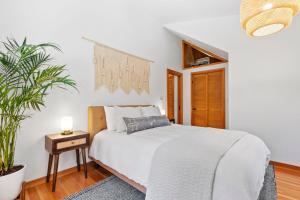 a white bedroom with a bed and a plant at Redwood Oasis - Luxe Santa Cruz Cabin w/ Hot Tub in Ben Lomond