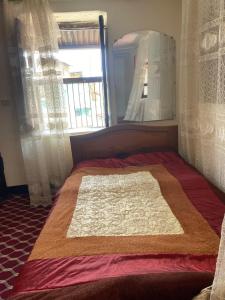 a bed with a blanket on it in a room with a window at Cultural guest house in Hārer