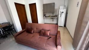 a brown couch in a living room with a kitchen at Apartamento 2 Quartos centro da cidade in Parauapebas +6 photos