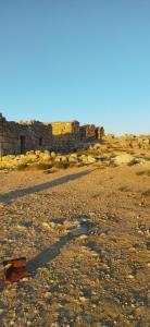an empty field with a brick building in the background at Welcome back in Al Hāshimīyah