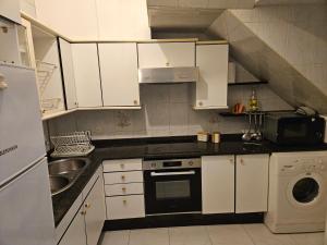 a kitchen with white cabinets and a sink and a dishwasher at Casa A Beira do Mar in O Grove +10 photos