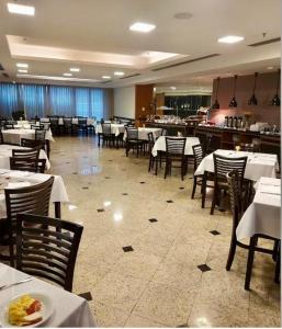 a dining room with white tables and chairs and a restaurant at Hotel Sol Alphaville1505 in Barueri