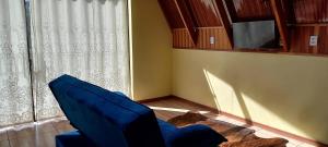 a blue chair in a room with a window at Chalé Raio de Sol- Colônia Witmarsum in Palmeira