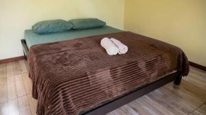 a bed with two pillows and two towels on it at Chalé Raio de Sol- Colônia Witmarsum in Palmeira