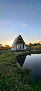 a small house with a large window next to a body of water at Chalé Raio de Sol- Colônia Witmarsum in Palmeira