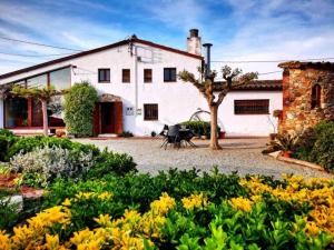 a house with a garden with yellow flowers at Can Micos - Masía de grupos 16 hasta 25 personas in Riudarenes