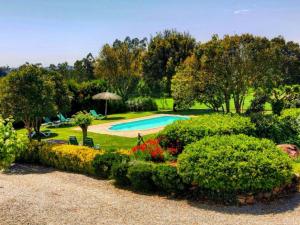 a garden with a swimming pool and some bushes at Can Micos - Masía de grupos 16 hasta 25 personas in Riudarenes