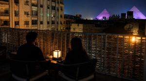 a man and a woman sitting at a table at night at The 5 Inn - Rooftop Pyramids View in Cairo
