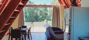 a living room with a dining table and a large window at Chalé Raio de Sol- Colônia Witmarsum in Palmeira