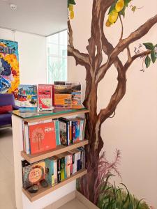 a book shelf with books and a tree painted on the wall at Barranco Boutique Hotel by 3B in Lima