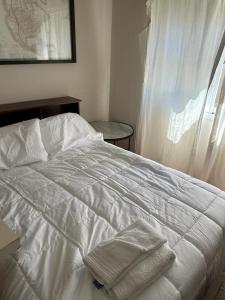 a white bed with two towels on top of it at Apart Jose in Comodoro Rivadavia
