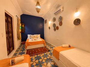 a bedroom with two beds and a blue wall at Riad Dar El Kaid in Fez