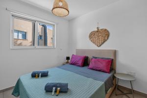 a bedroom with a bed with purple pillows and a window at WAKE UP BY THE SEA BEACHFRONT FLATS - Protaras in Protaras +65 photos