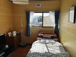 a bedroom with a bed and a window and a table at 民宿とまとハウスTomato House in Funehiki