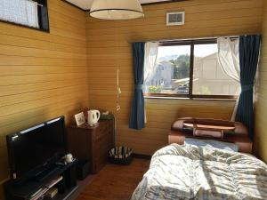 a bedroom with a bed and a tv and a window at 民宿とまとハウスTomato House in Funehiki