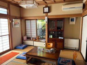 a living room with a table and a kitchen at 民宿とまとハウスTomato House in Funehiki