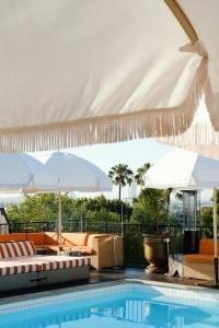 a swimming pool with chairs and umbrellas and a pool at Petit Ermitage in Los Angeles