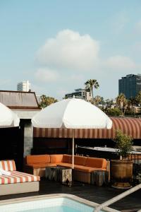 a patio with a large umbrella and chairs and a pool at Petit Ermitage in Los Angeles