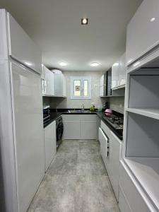 a large white kitchen with white cabinets and appliances at Retaj Waterfront Penthouse in Port Said
