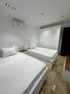 two beds in a room with white walls at Retaj Waterfront Penthouse in Port Said