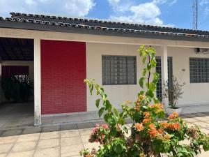 a house with a red door and some flowers at Casa no centro in Primavera do Leste