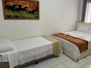 a bedroom with two beds and a painting on the wall at Casa no centro in Primavera do Leste