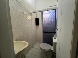 a bathroom with a toilet and a sink and a shower at peruibe pousada na areia in Peruíbe