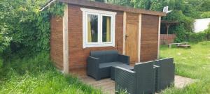a small wooden shed with a window and a bench at Domek GLAMPING na Polu namiotowym RADOŚĆ in Okuninka