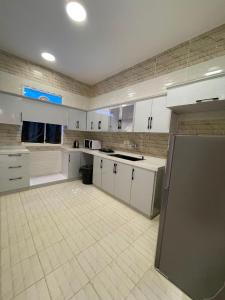 a large kitchen with white cabinets and a tile floor at شقق سكنية مريحة in Tanomah +17 photos