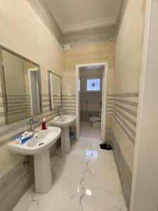 a bathroom with two sinks and mirrors and a toilet at شقق سكنية مريحة in Tanomah