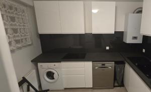 a kitchen with a washing machine and white cabinets at 10 mn Paris in Gennevilliers