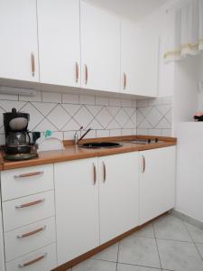 a kitchen with white cabinets and a white refrigerator at Apartments and rooms by the sea Moscenicka Draga, Opatija - 7767 in Mošćenička Draga