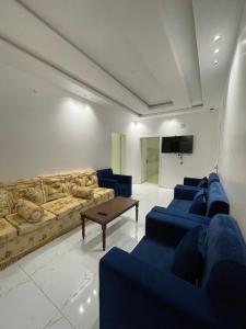 a living room with blue couches and a tv at شقق سكنية مريحة in Tanomah