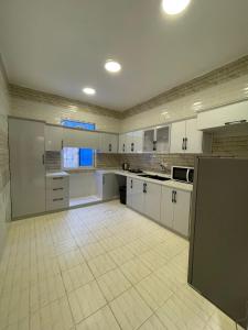 a large kitchen with white cabinets and a tile floor at شقق سكنية مريحة in Tanomah