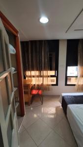 a bedroom with a bed and a chair and windows at Nekor Bay Appartement in Al Hoceïma +4 photos