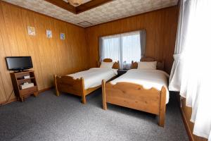 a bedroom with two beds and a tv and a window at 暮泊くらはく 1日 1組様限定 5名様まで宿泊可能 in Mikasa
