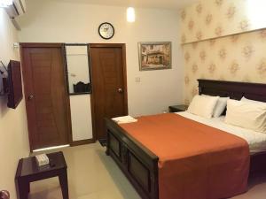a bedroom with a bed and a clock on the wall at Hotel Moon Light view in Lahore